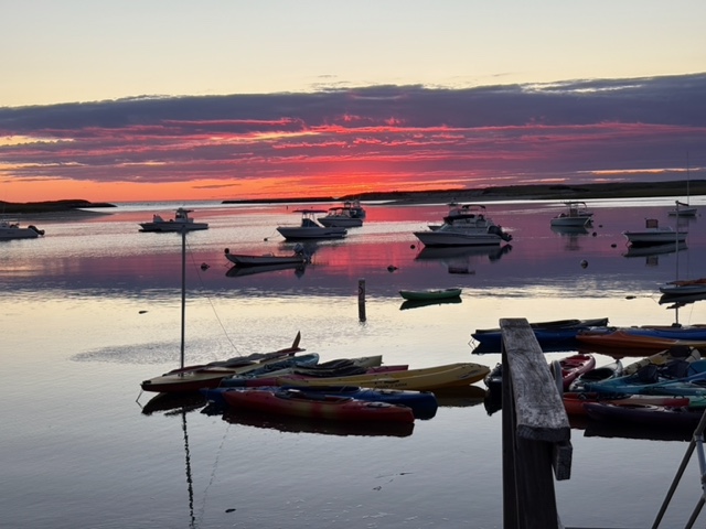 Sunset over Pamet Harbor with moored boats and kayaks